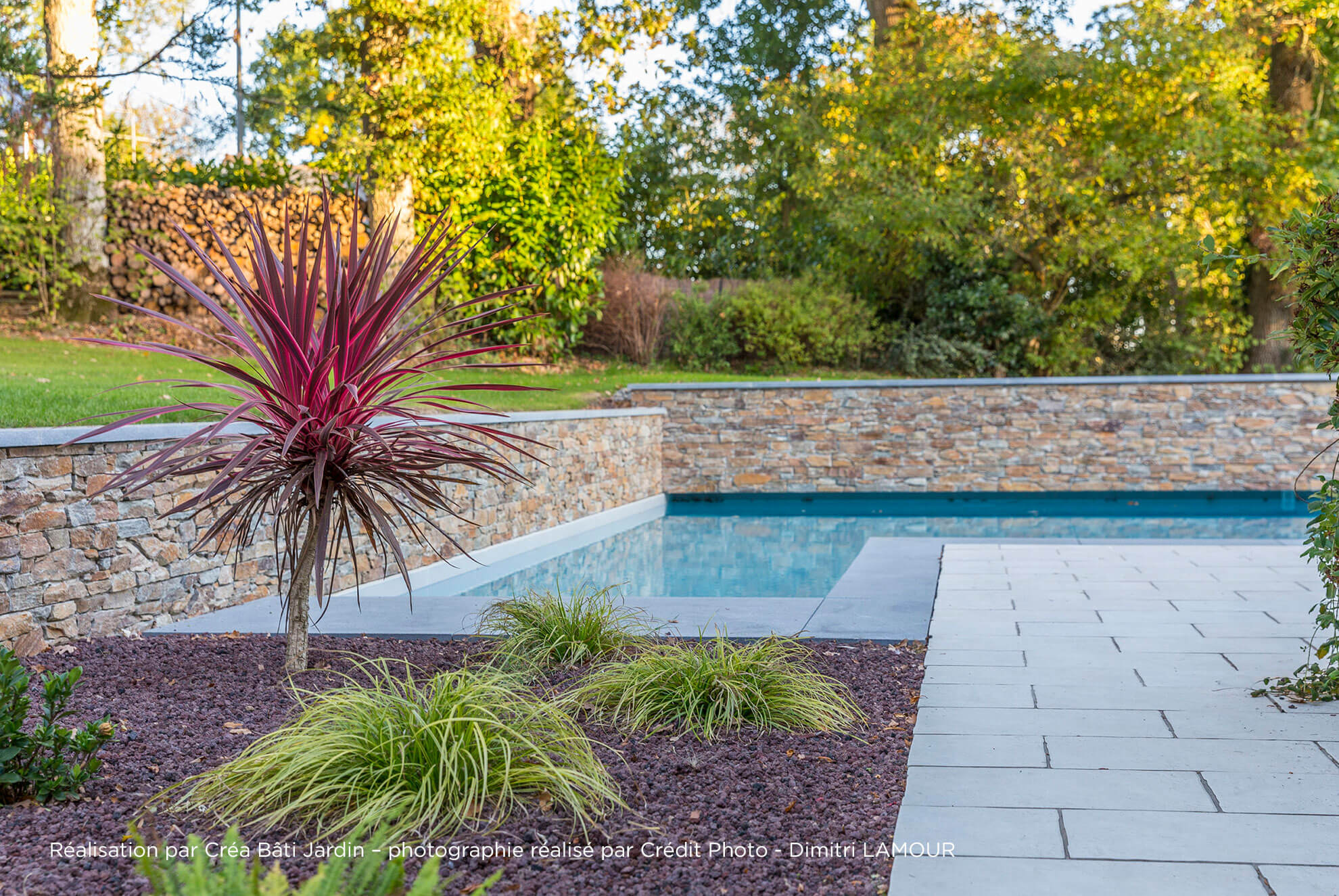 Zone de piscine d'une maison familiale, la zone de piscine est délimitée par un muret en Stonepanel, et les margelles de la piscine sont en calcaire bleu d'Asie. Travaux réalisés par Crea Bati Jardin.